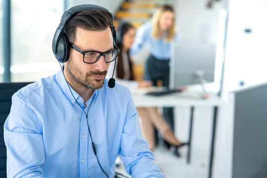 Focused customer support specialist with a headset working at his desk