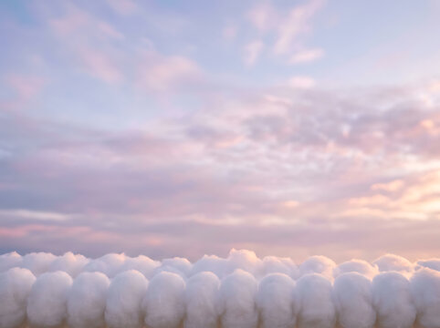 Row of soft white pom cotton texture aligned against pastel sunset sky with cloud simulation sky background aligned objects still life atmosphere creative