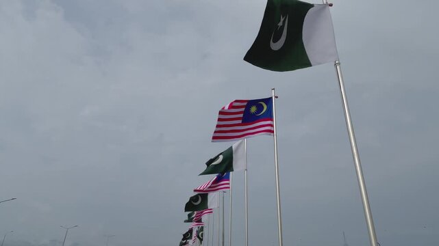 Pakistan and Malaysia Flags Waving Together Against a Dramatic Cloudy Sky, International Relations Concept