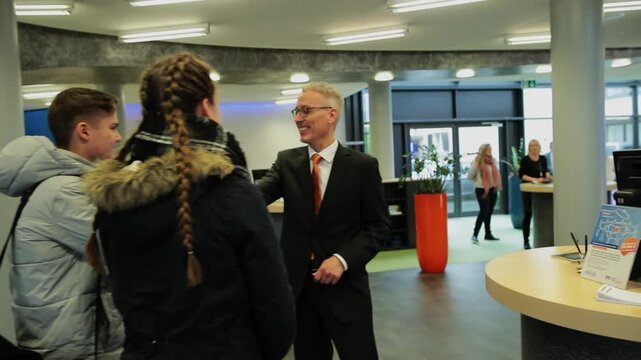 Corporate employee greets visitors in a modern office reception area, representing client meetings, contractor visits, workplace communication and professional networking