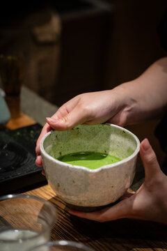 點てられた温かいお抹茶が注がれた和陶器の茶碗を両手で持つ様子