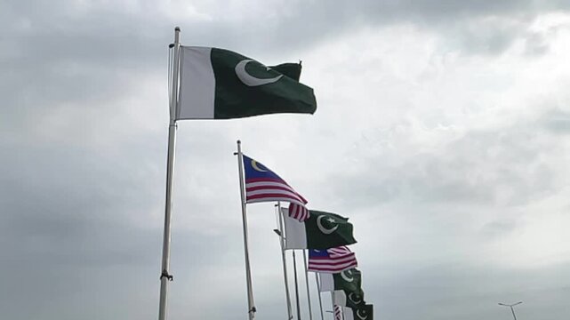Pakistan and Malaysia National Flags Waving Together in Slow Motion Under a Cloudy Sky