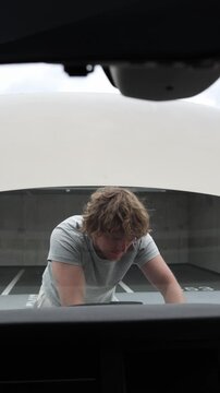 Vertical screen proud car owner stands by the open hood smiling with great relief after successfully repairing the vehicle himself and solving the hard mechanical problem