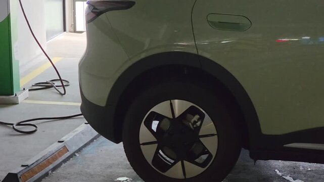 Electric vehicle charging in underground parking garage, car connected to power supply station, sustainable energy for modern transportation