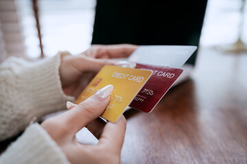 Woman holding multiple credit cards beside a laptop, representing online shopping, payment options,...
