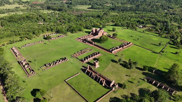 Aerial overview of the historic Jesuit Missions ruins and ancient stone structures on green grass in Paraguay.