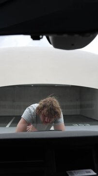 Vertical screen persistent car owner keeps repairing his own vehicle under the open hood declining to surrender while struggling with a difficult mechanical problem alone
