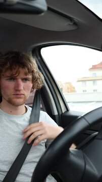 Vertical screen driver pulls the seat belt across his body and secures it before starting the sedan showing a proper safety routine and responsible preparation for travel
