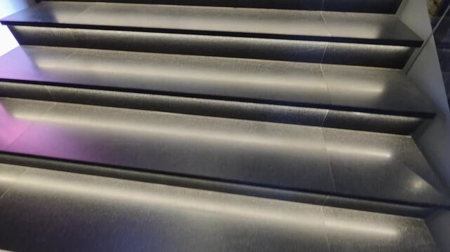 Modern architectural staircase design with elegant strip lighting illuminating each dark step, creating a sleek and contemporary interior perspective of upward path