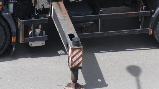 Construction vehicle outrigger providing stability on asphalt pavement during day, a critical component of heavy machinery support system, ensuring safety and operational integrity, truck crane