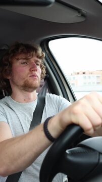 Vertical screen inexperienced driver seems uncertain behind the wheel making hesitant decisions while carefully handling the car and adapting to challenging urban traffic