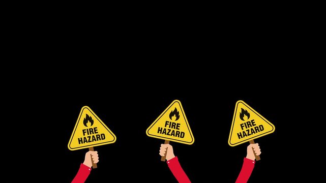 Hands holding yellow fire hazard warning signs on black background