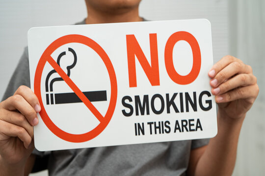 Male holding a no smoking sign.