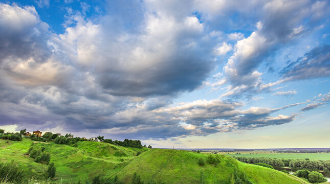Vast green hills roll beneath a dynamic sky