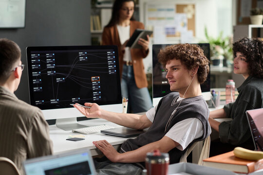 Young man explains coding on computer to university study group
