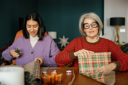 Mother and daughter wrap a Christmas present indoors