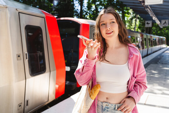 Woman records voice message at outdoor train station platform