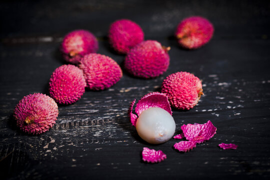 Whole and peeled lychee on dark wood
