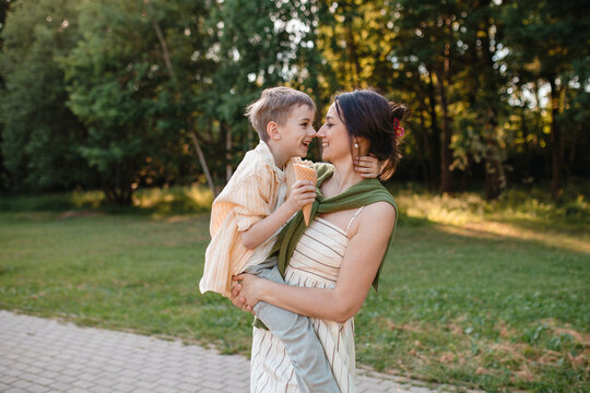 A happy mother holds her smiling son with ice cream in the park