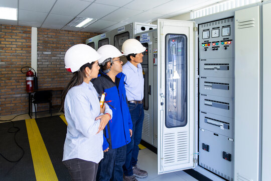 Engineer team examines an electrical control box in a control room
