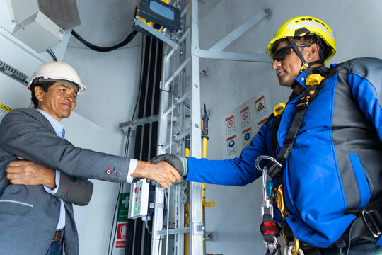 Engineer and technician shake hands inside a wind turbine base