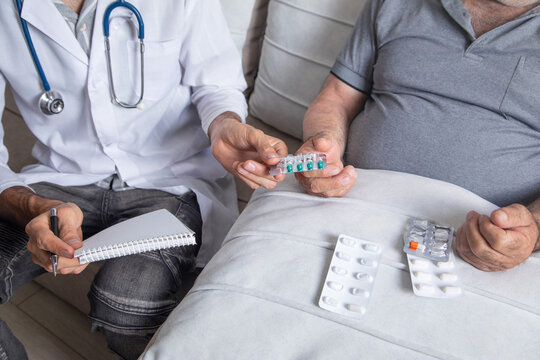 Doctor giving medical pills in patient at home.