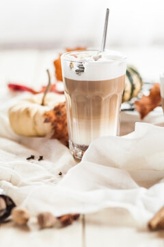 Glass of pumpkin spice Latte Macchiato in between autumnal decoration
