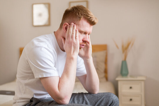 Man with headache sitting indoors holding head showing stress