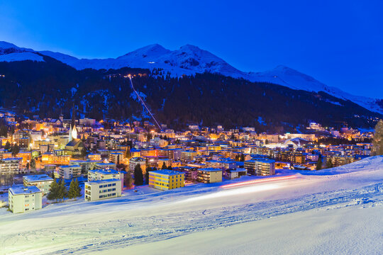 Illuminated Schatzalp funicular rises above snowy Davos at night
