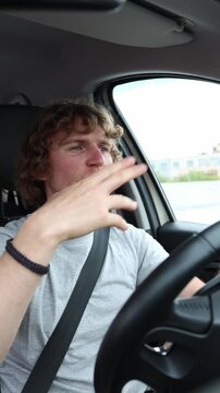 Vertical screen happy driver listens to music and dances behind the wheel enjoying the rhythm while the car moves through urban traffic during a lively and upbeat journey