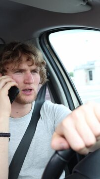 Vertical screen motorist holds a phone conversation behind the wheel dividing attention between the caller and changing road conditions while navigating a busy urban route