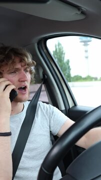 Vertical screen driver talks on a mobile phone while operating a moving car through busy city traffic creating a dangerous distraction and road safety risk during commute