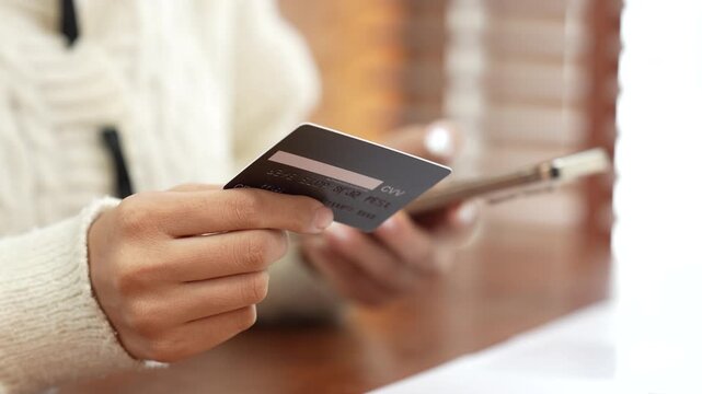 Woman holding a credit card and smartphone, representing online shopping, digital payment, e-commerce, mobile banking and cashless transactions.