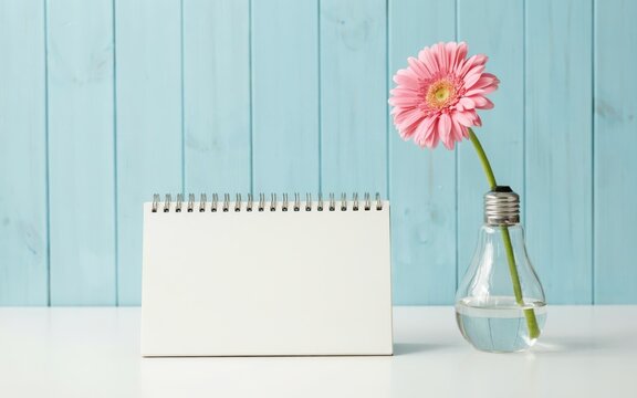 Blank spiral calendar with a pink gerbera flower in a light bulb vase