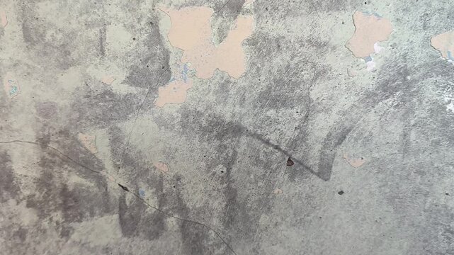 Detailed view of a cracked, weathered concrete wall showing peeling layers of old paint, ideal for background texture use.