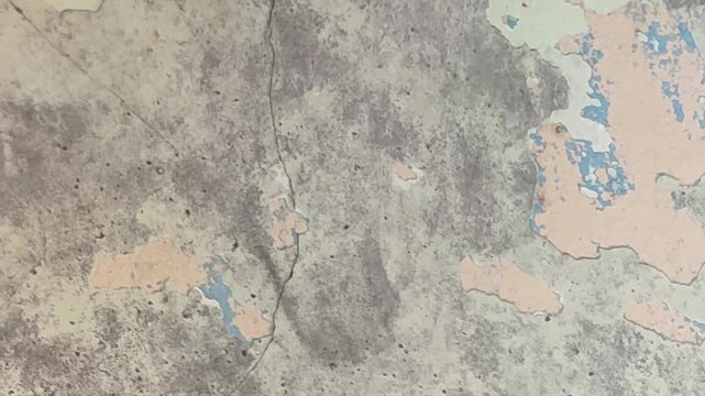 Close-up loop of a weathered cement wall surface featuring cracked, peeling paint and a gritty industrial texture for overlay use.