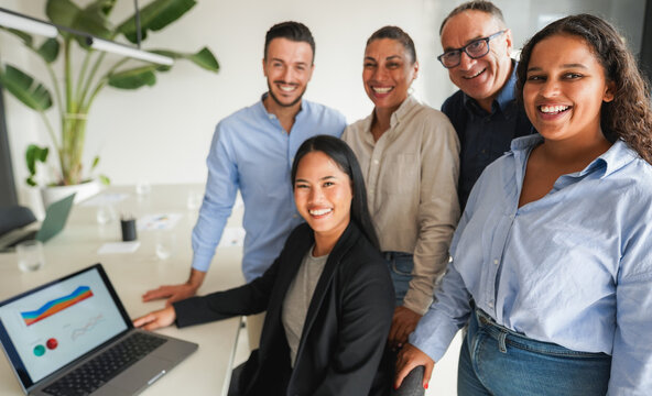 Multiracial business people smiling on camera inside company office - Multi generational colleagues having fun together - Corporate concept - Main focus on right girl face - UGC content