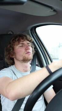 Vertical screen tired driver drives home after a demanding work shift struggling with exhaustion while moving through busy city traffic during a stressful evening commute
