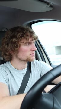 Vertical screen sleepy driver struggles to remain alert behind the wheel while continuing to drive through busy traffic creating a very unsafe situation on the urban road