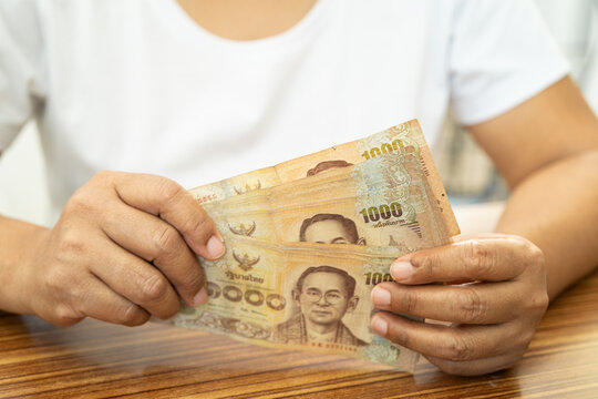 Asian business woman holding Thai banknote currency money.