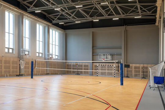 Empty indoor basketball and volleyball sports hall with markings and wooden parquet floor. Real Photo