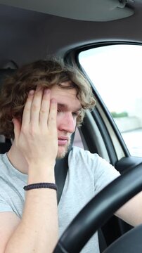 Vertical screen tired driver rubs painful eyes and struggles to stay awake while driving through traffic showing severe fatigue and dangerous sleepiness during daily trip