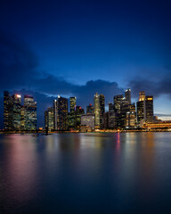 Naklejka premium Singapore Marina Bay Skyline at Blue Hour with Illuminated Downtown Buildings and Waterfront Reflections