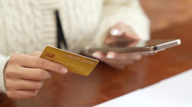Woman holding a credit card and smartphone, representing online shopping, digital payment, e-commerce, mobile banking and cashless transactions.