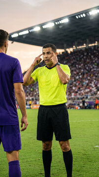 Referee explains decision to football player during tense stadium match. Concept of sports communication, conflict management and fair play.