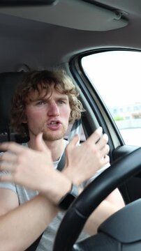 Vertical screen driver dances behind the wheel and gestures to the beat while traveling through the city happily enjoying a song and becoming distracted from safe driving