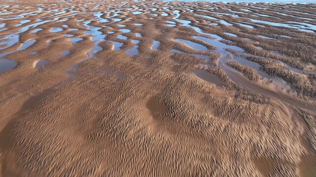Sand Patterns With Tidal Pools At Golden Hour. Low Fast Flight Revealing Wide Tidal Pool. Fleetwood, Lancashire, England, UK.
