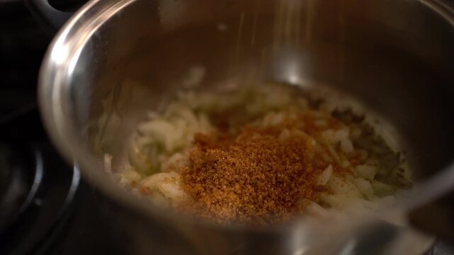A pan of onions cooks slowly in olive oil as brown sugar is added, a step before making tomato sauce