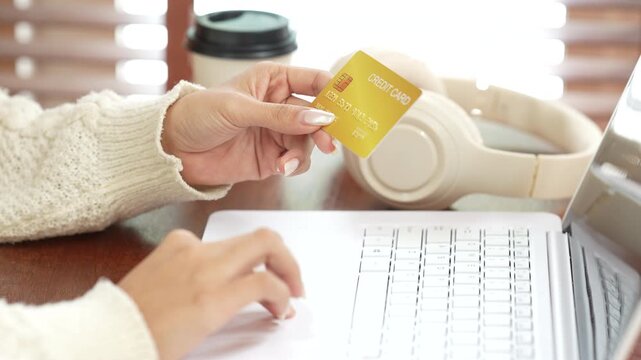 Woman using a laptop while holding a credit card, representing online shopping, digital payment, e-commerce and secure financial transactions.