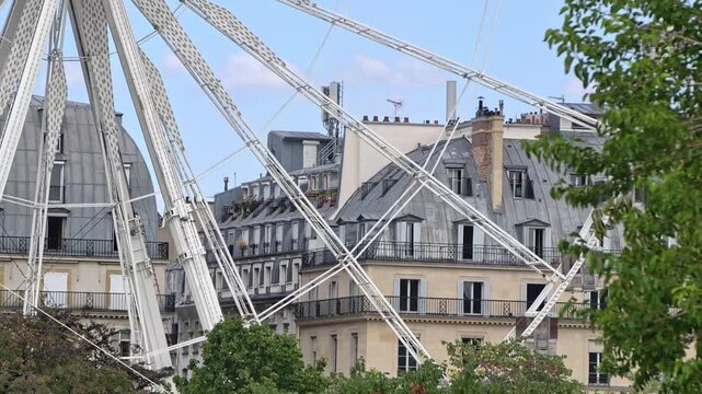Close Up View Of The Structure And Spokes Of The Ferris Wheel Against Historic Paris Rooftops